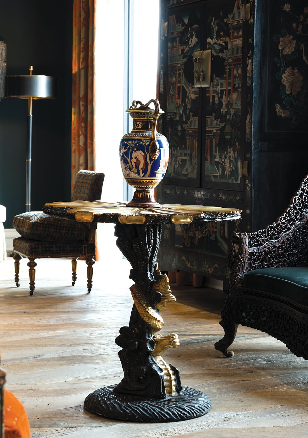 A 19th-century porcelain vase sits atop a 20th-century vintage carved-giltwood seahorse table