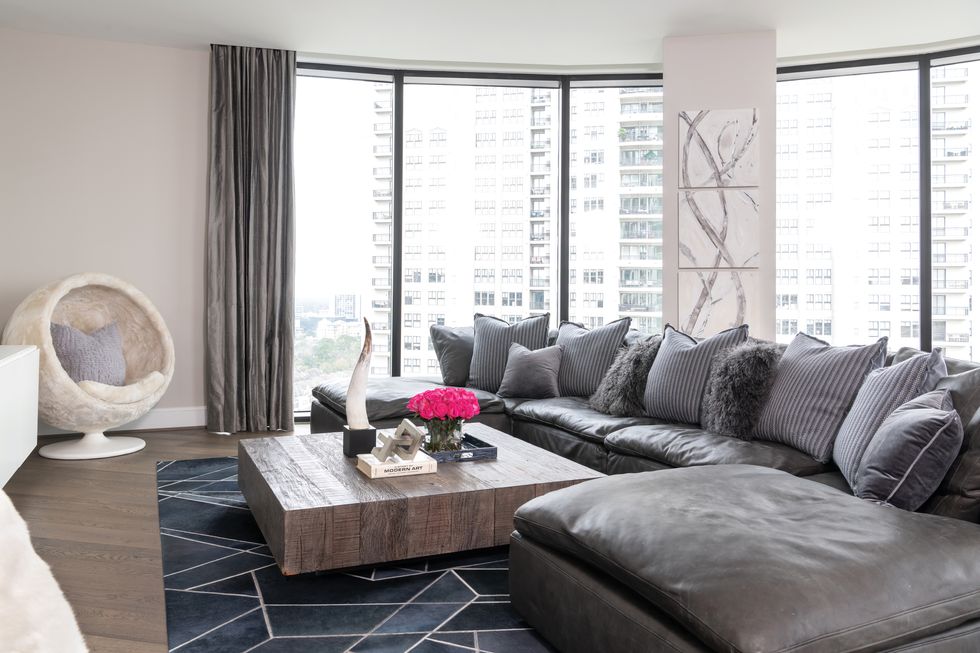 Masculine hues and a custom geometric cowhide rug from BeDesign anchor the otherwise light-and-bright living room