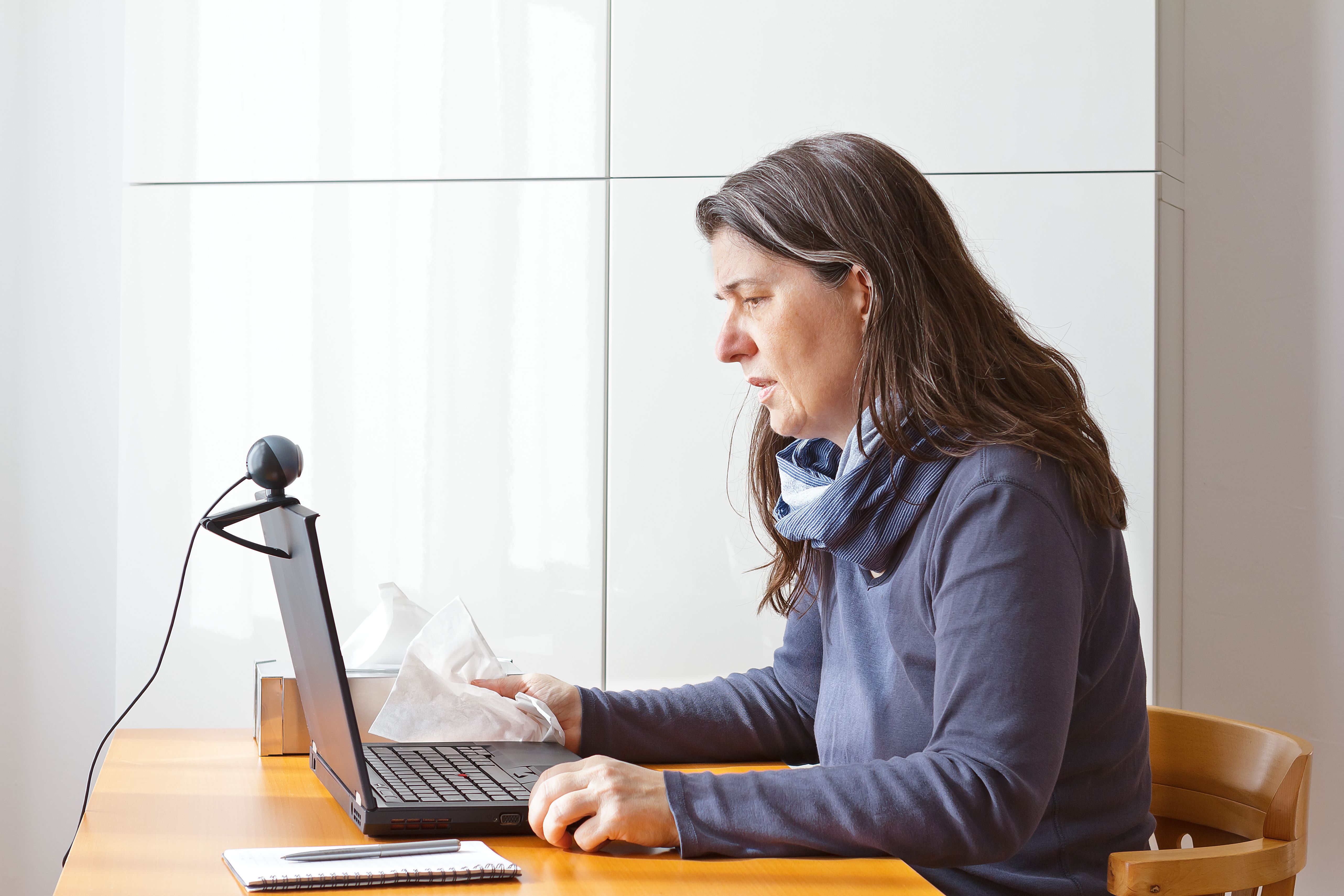 Video consult: woman with a cold calling her doctor on a laptop via video link.